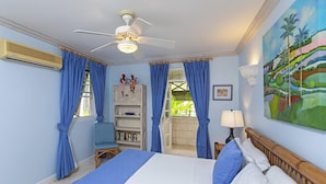 A bedroom with a bed, a ceiling fan, a window with curtains, a bookshelf, and a painting on the wall. - Blue Haven (Bowling Alley Hill)