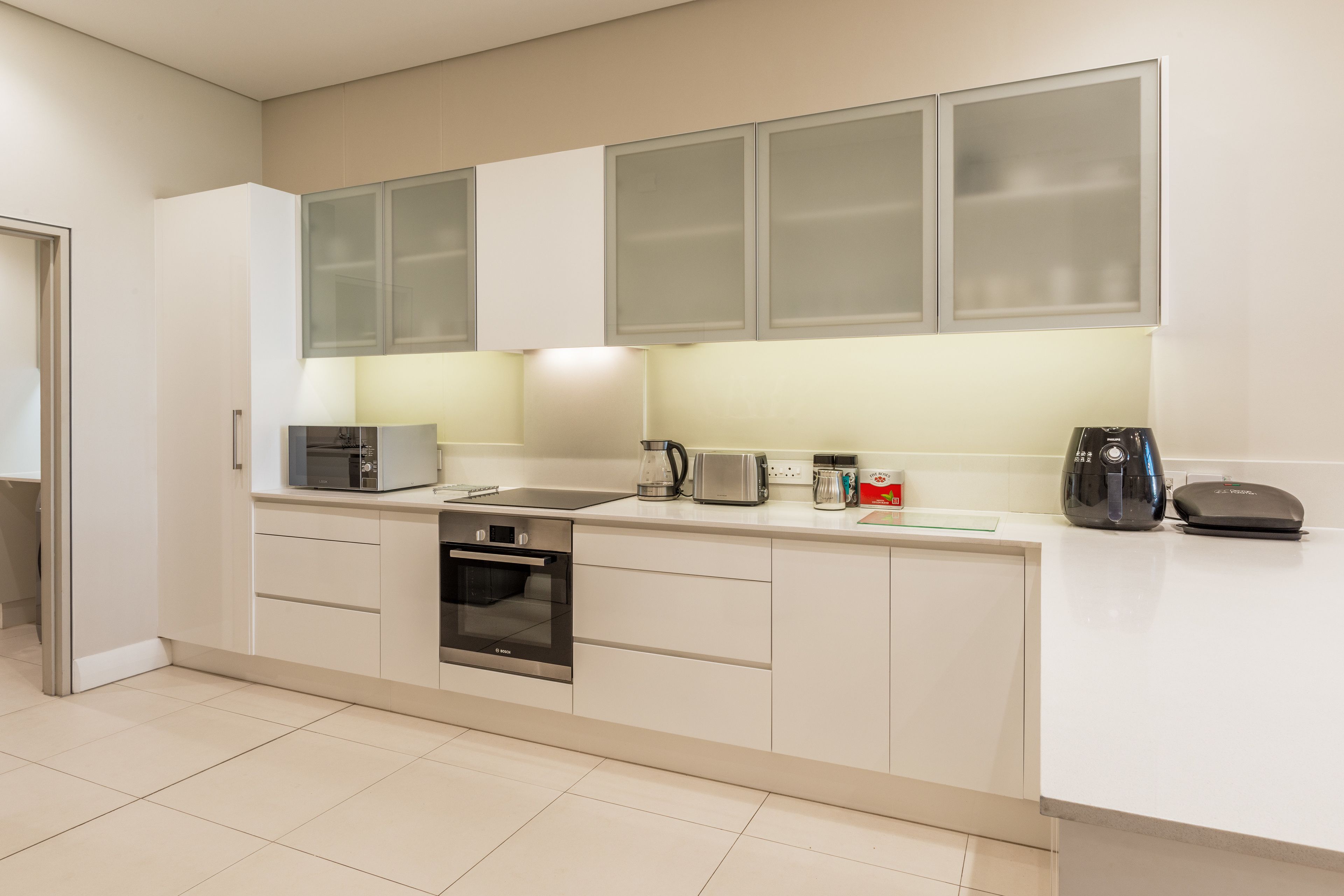 A modern kitchen with white cabinets, a built-in oven, a coffee maker, and a toaster.