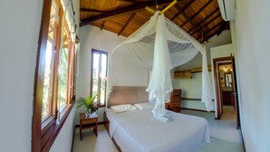 A bedroom with a canopy bed, wooden ceiling beams, a nightstand, a dresser, and a window with a plant. - Trancoso Residence (Porto Seguro)