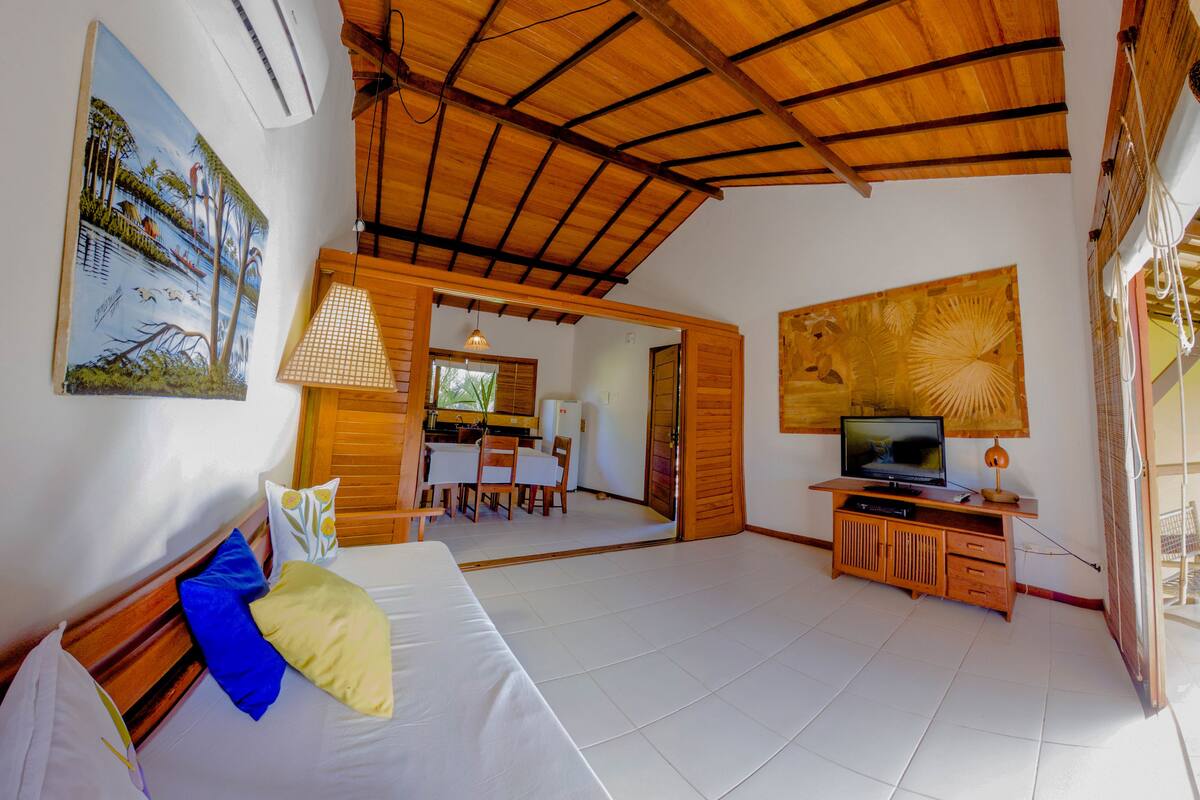 Una habitación con cama, televisión, aparador de madera y zona de comedor.