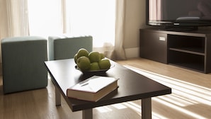 A modern living room with a wooden coffee table, a bowl of green apples, and a book. - Hostal Goya (Barcelona)