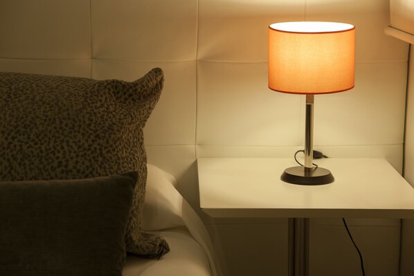 A bedside table with a lamp, a pillow, and a wall-mounted light fixture. - Hostal Goya (Barcelona)