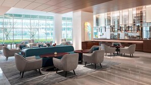 A modern hotel lobby with a bar area, seating arrangements, and large windows offering views of the outdoors. - Courtyard by Marriott Shanghai Minhang (Shanghai)