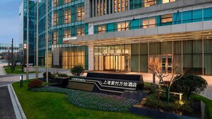 A Courtyard hotel with a modern glass facade, a well-lit entrance, and landscaped gardens. - Courtyard by Marriott Shanghai Minhang (Shanghai)