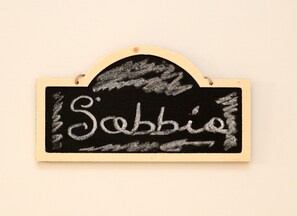 Un letrero de pizarra con el nombre 'Sophie' escrito, sujeto a una pared con marco de madera.
