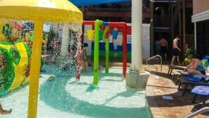 Ett område i vattenparken med en blå vattenrutschkana, en gul vattenattraktion och en pool med solstolar.