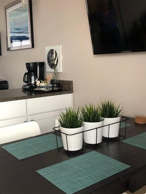 A modern kitchen with a coffee maker, a framed picture, and a TV mounted on the wall. - Caravelle 1401 (Myrtle Beach)