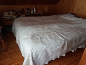 Un dormitorio con una cama grande, paredes de madera y suelo de madera.