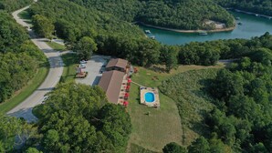 Vue aérienne d’une propriété comprenant une piscine, une route et une étendue d’eau.