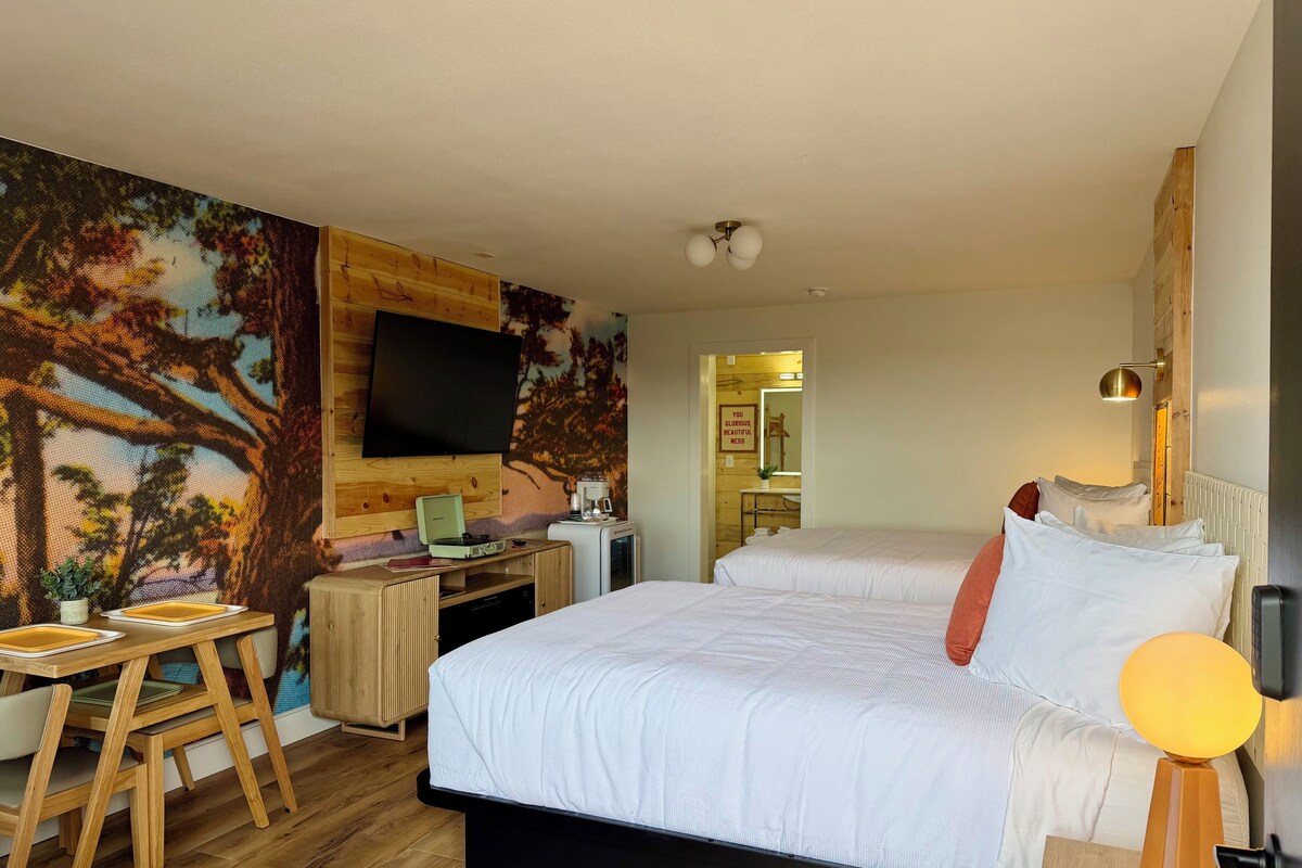 A hotel room with a bed, desk, and a wall-mounted TV.