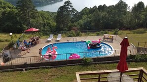 Une piscine avec des jeux gonflables, entourée d’une terrasse dotée de chaises longues et d’une table de pique-nique.