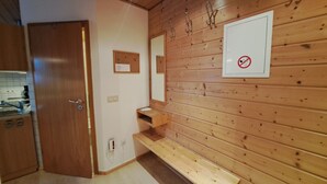 A wooden interior with a door, a mirror, a towel rack, and a no-smoking sign. - Vacation apartment no. 1 (Neuötting)