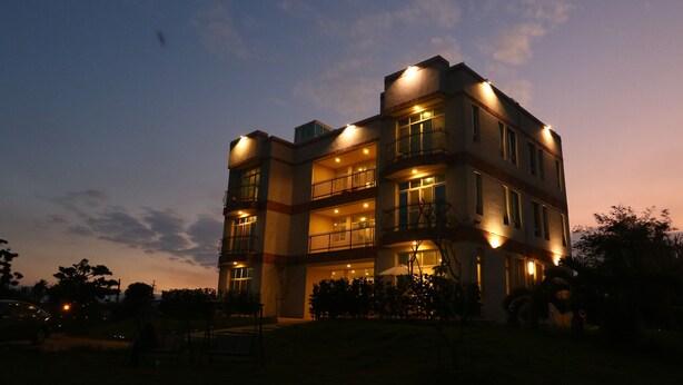 A multi-story building with balconies and illuminated windows at dusk. - Full Moon Resort (Hengchun)