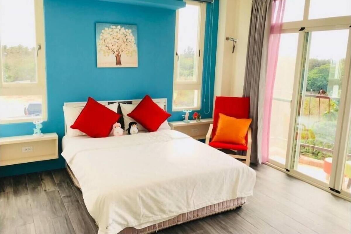 A bedroom with a bed, a nightstand, a chair, a window, and a painting.