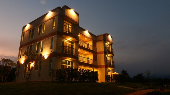 A multi-story building with balconies and warm lighting. - Full Moon Resort (Hengchun)