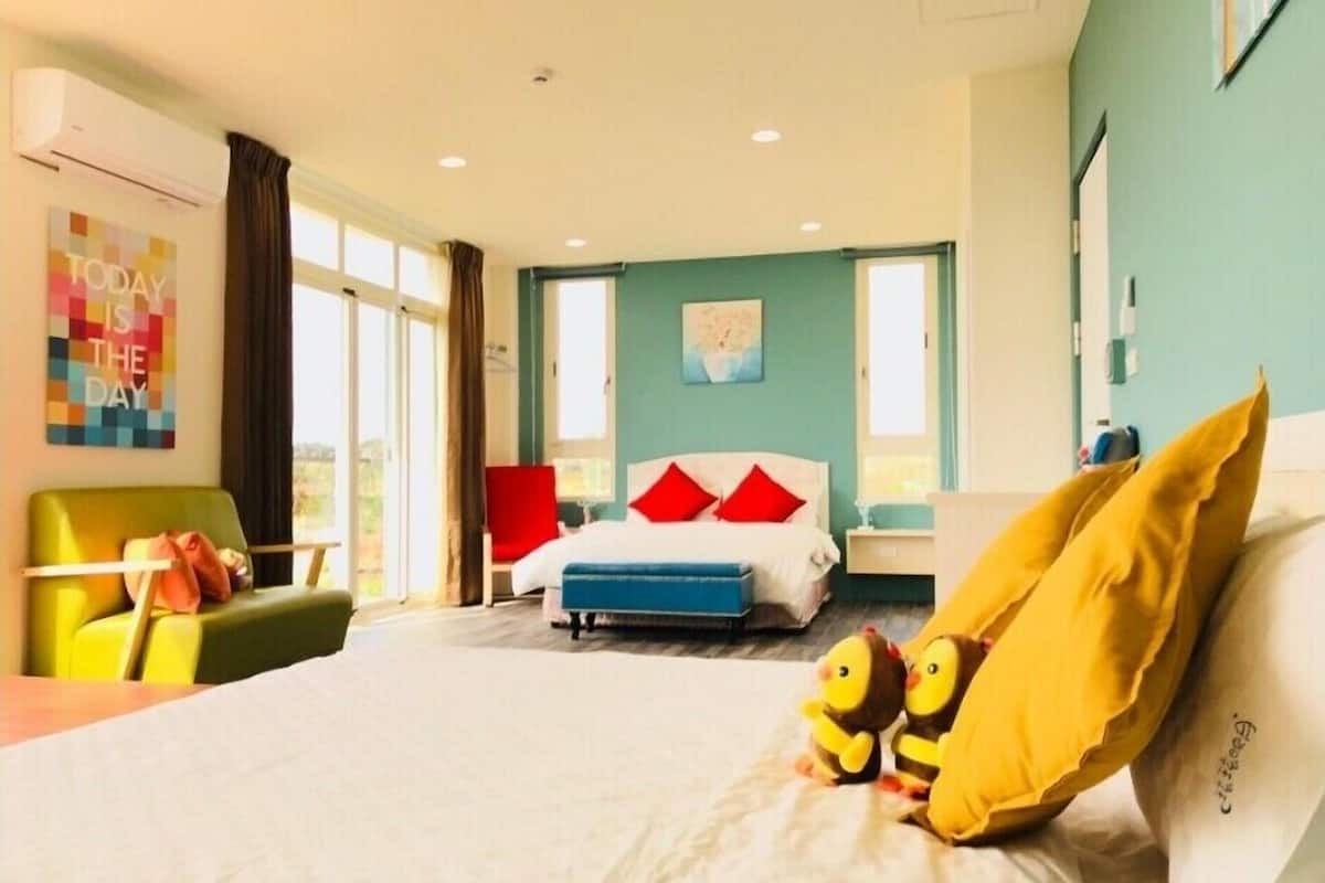 A hotel room with a bed, a chair, a desk, and a window.