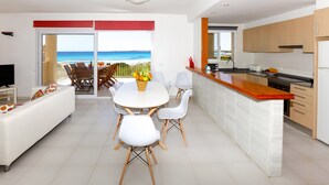 Una cucina moderna con mobili bianchi, un piano di lavoro in legno e vista sull'oceano.