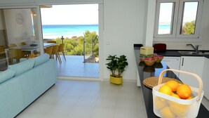 Una cucina moderna con vista sull'oceano, un'area pranzo con un divano blu e una pianta in vaso.