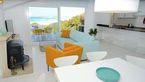 Un soggiorno moderno con divano, poltrone e tavolo da pranzo. Si gode di vista sull'oceano grazie a ampie finestre.