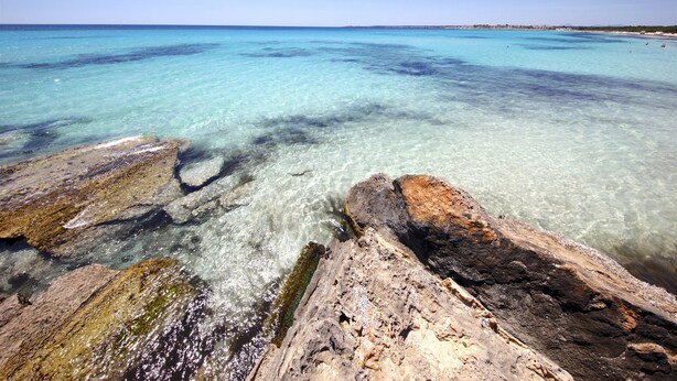Una costa rocciosa con acque turchesi cristalline.