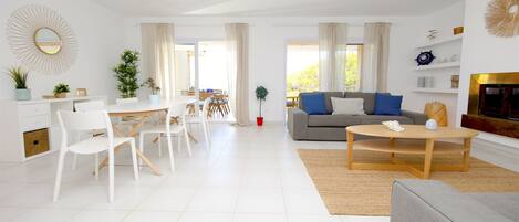 A modern living room with a dining area, a grey sofa, and a coffee table.