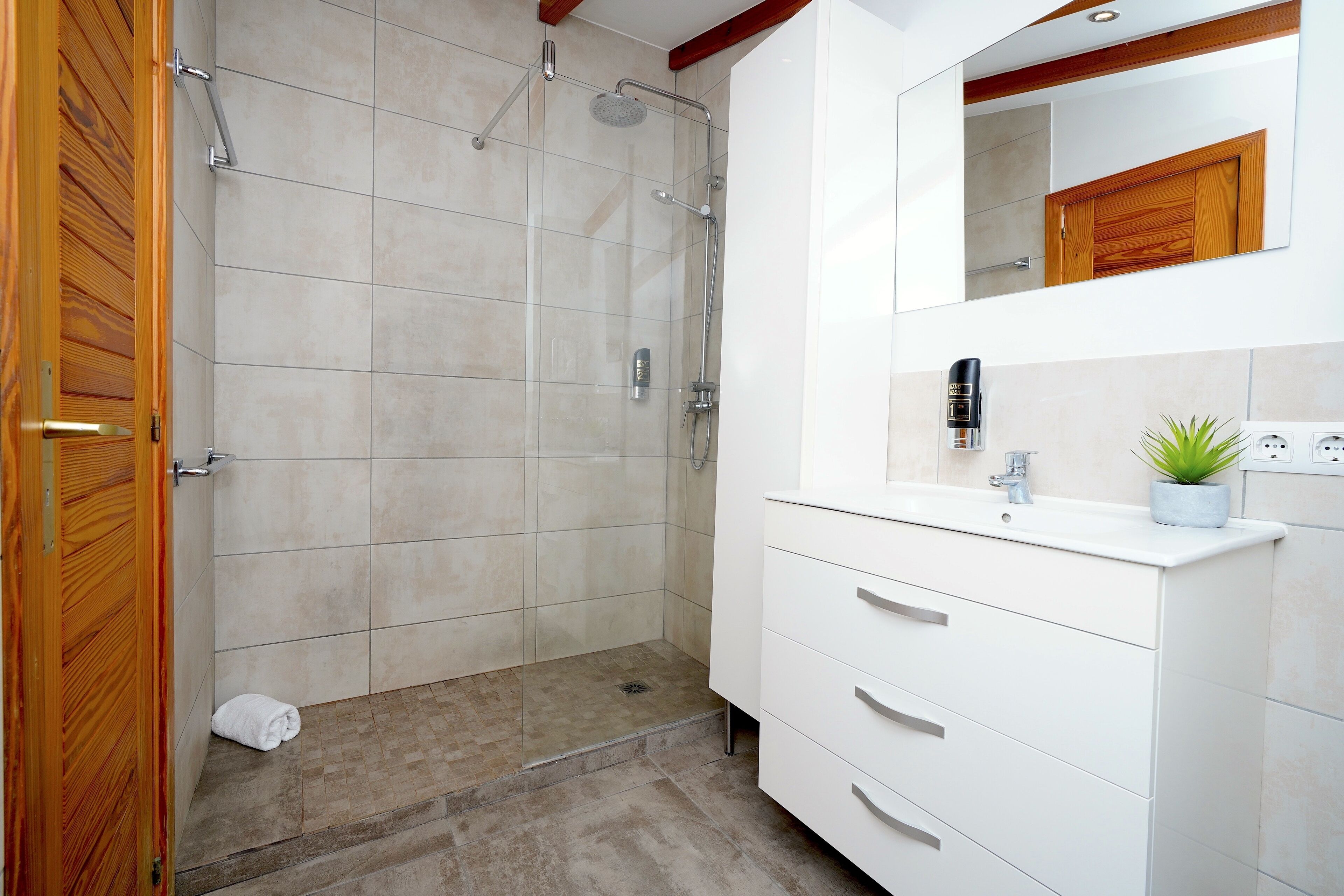 A bathroom with a shower, a sink, and a mirror.