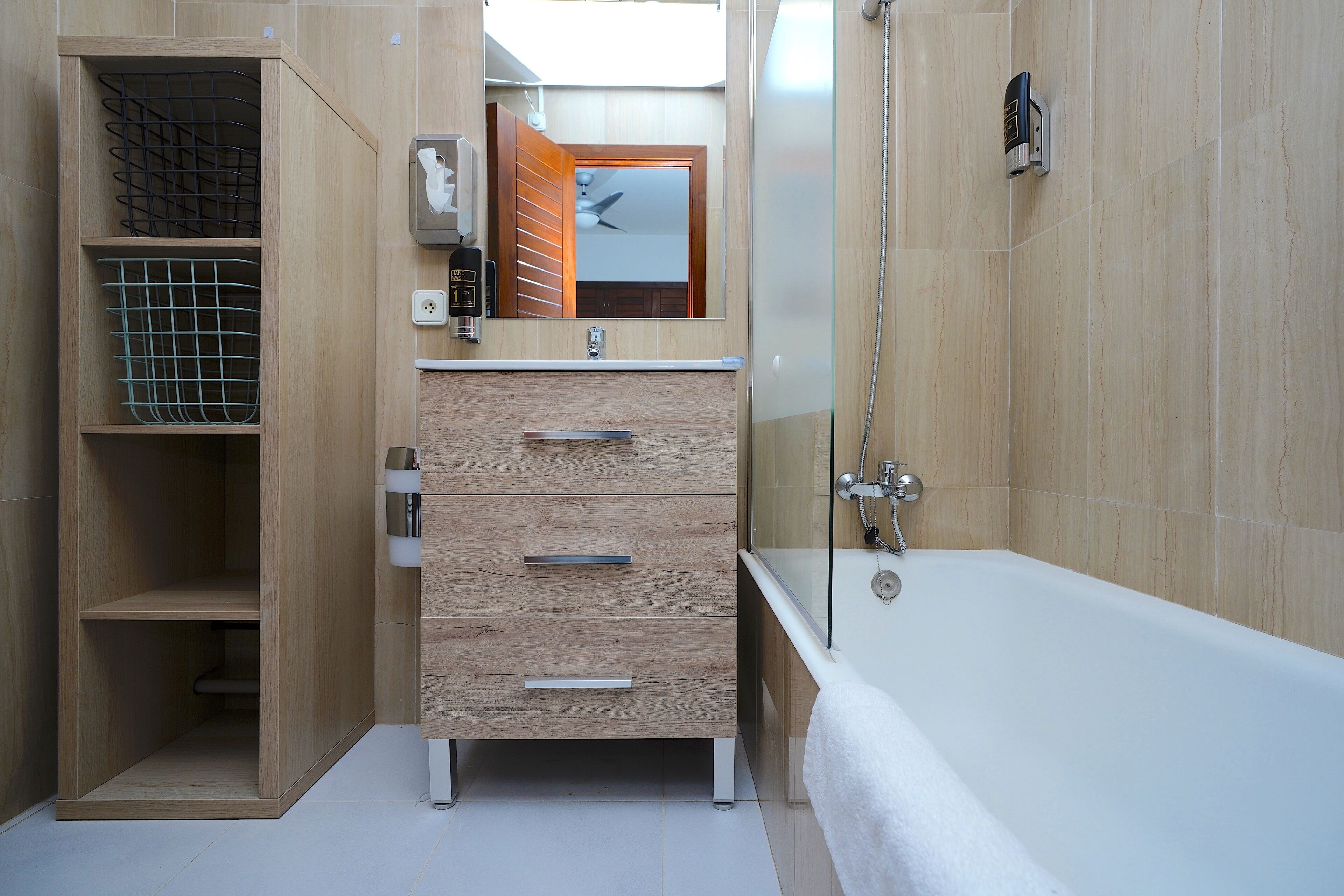 A modern bathroom with a wooden vanity, a glass shower enclosure, and a visible ceiling fan.