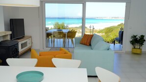 Un soggiorno moderno con un'ampia porta scorrevole in vetro che si apre su un balcone con vista sull'oceano.