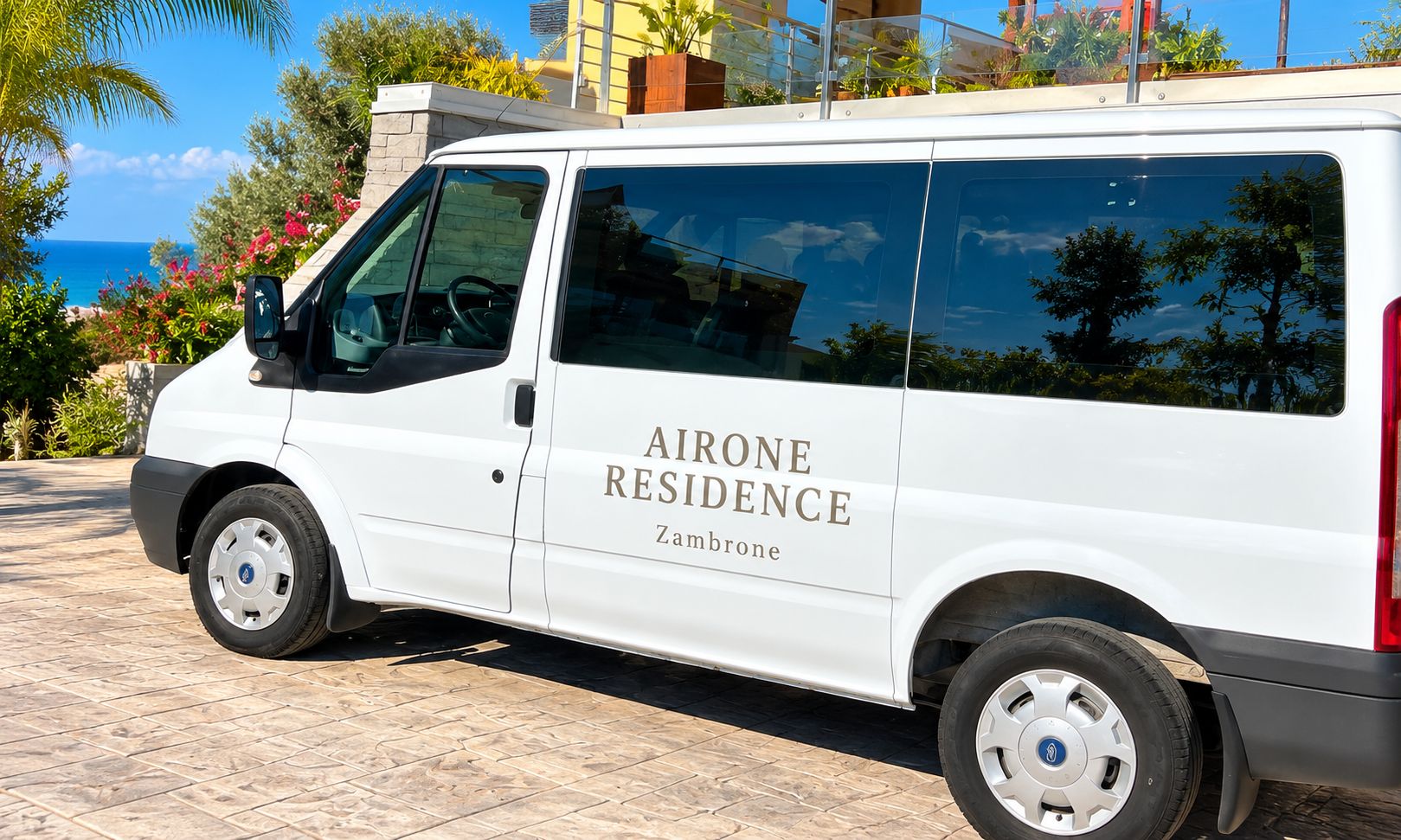 Ein weißer Van mit der Aufschrift 'AIRONE RESIDENCE' und 'Zambrone'.