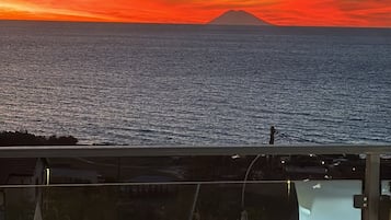 Sonnenuntergangblick von einem Balkon mit Pool und Liegestühlen.