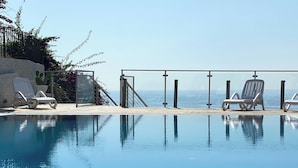 A clear swimming pool with lounge chairs and a view of the sea. - Airone Residence (Zambrone)
