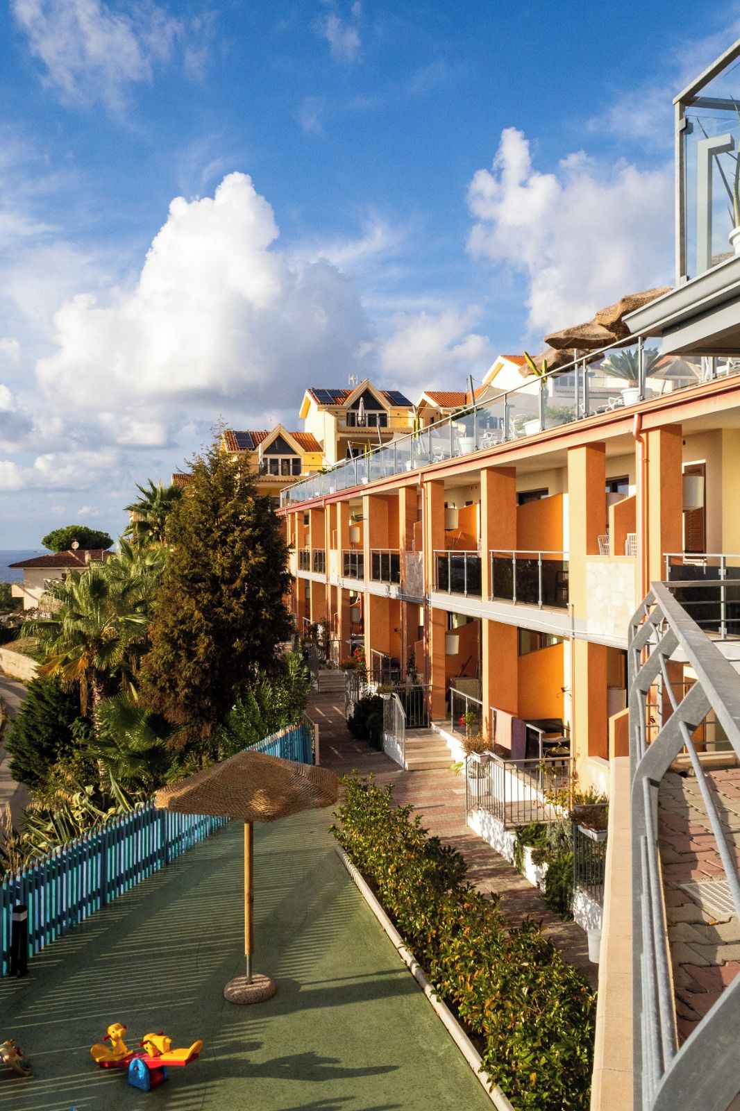 A hotel with multiple floors, outdoor swimming pool, and a children's play area.