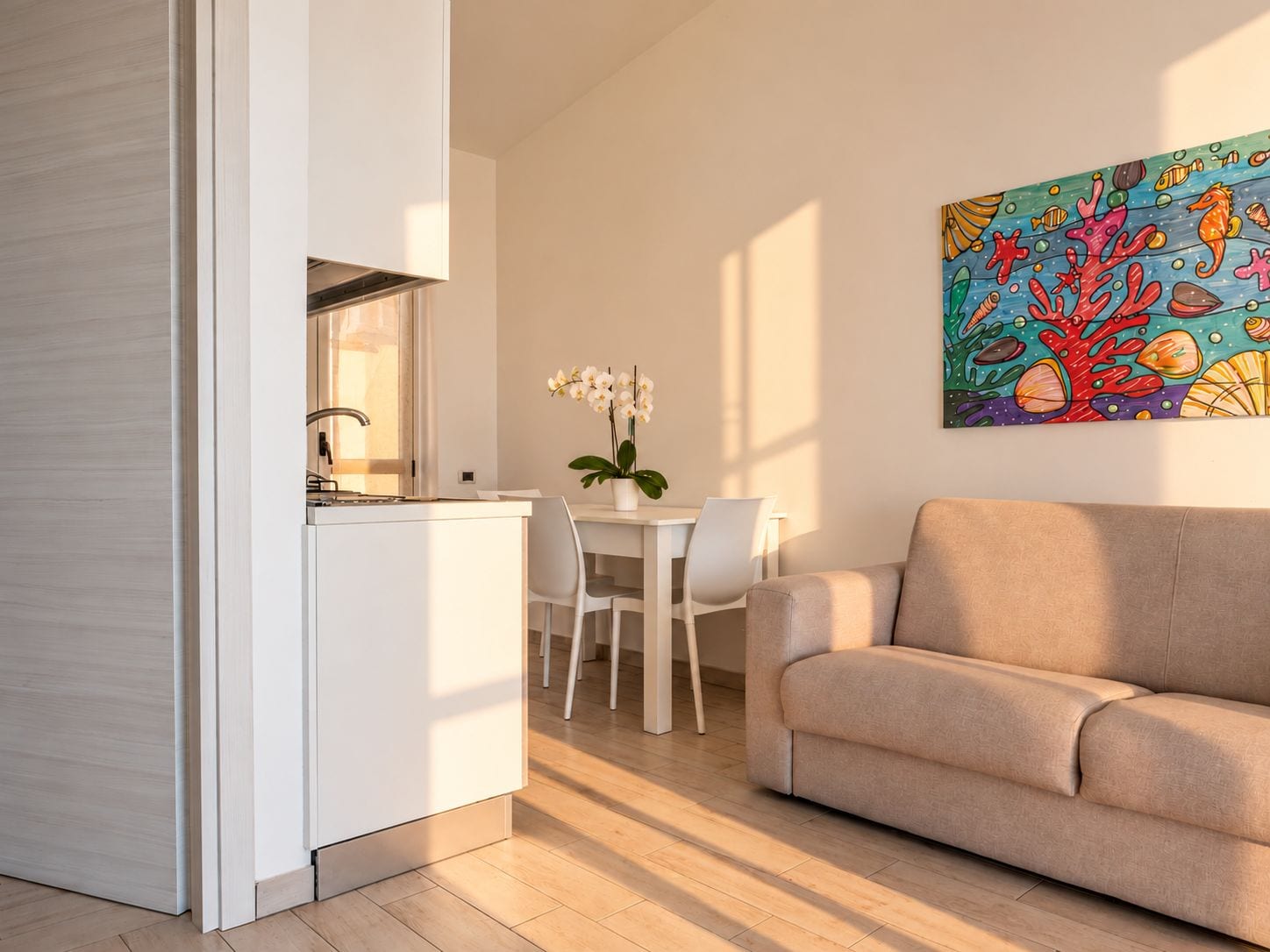 Una cocina moderna con encimera blanca y un comedor con mesa y sillas blancas.