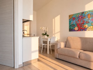 Una cocina moderna con encimera blanca y un comedor con mesa y sillas blancas.