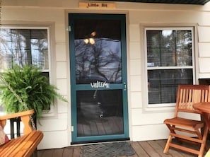 A front door with a 'Welcome' sign, a bench, and a chair outside. - Little Bit of Heaven (Mineral Bluff)