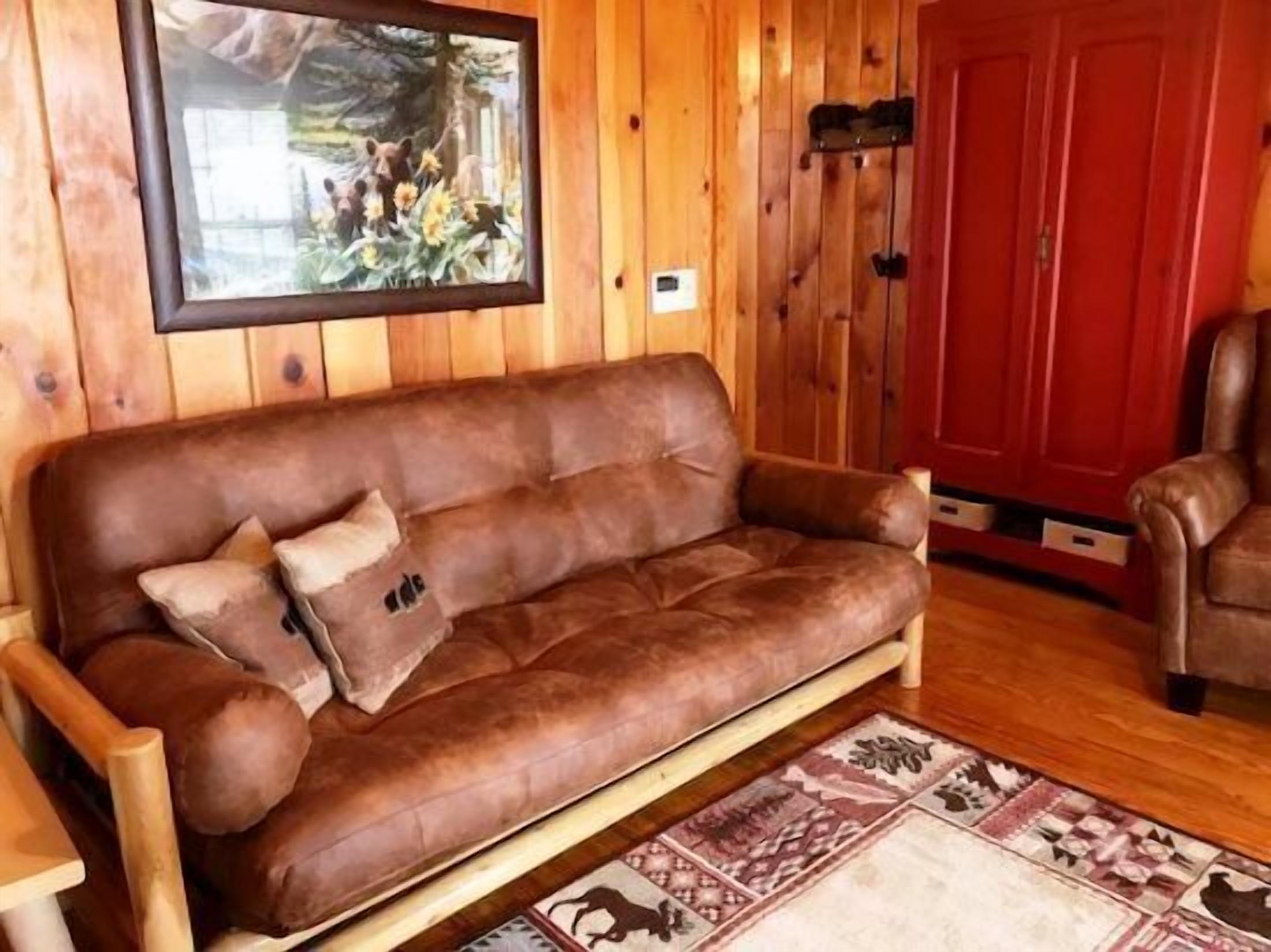 A brown leather sofa with a patterned rug and a framed picture on the wall.