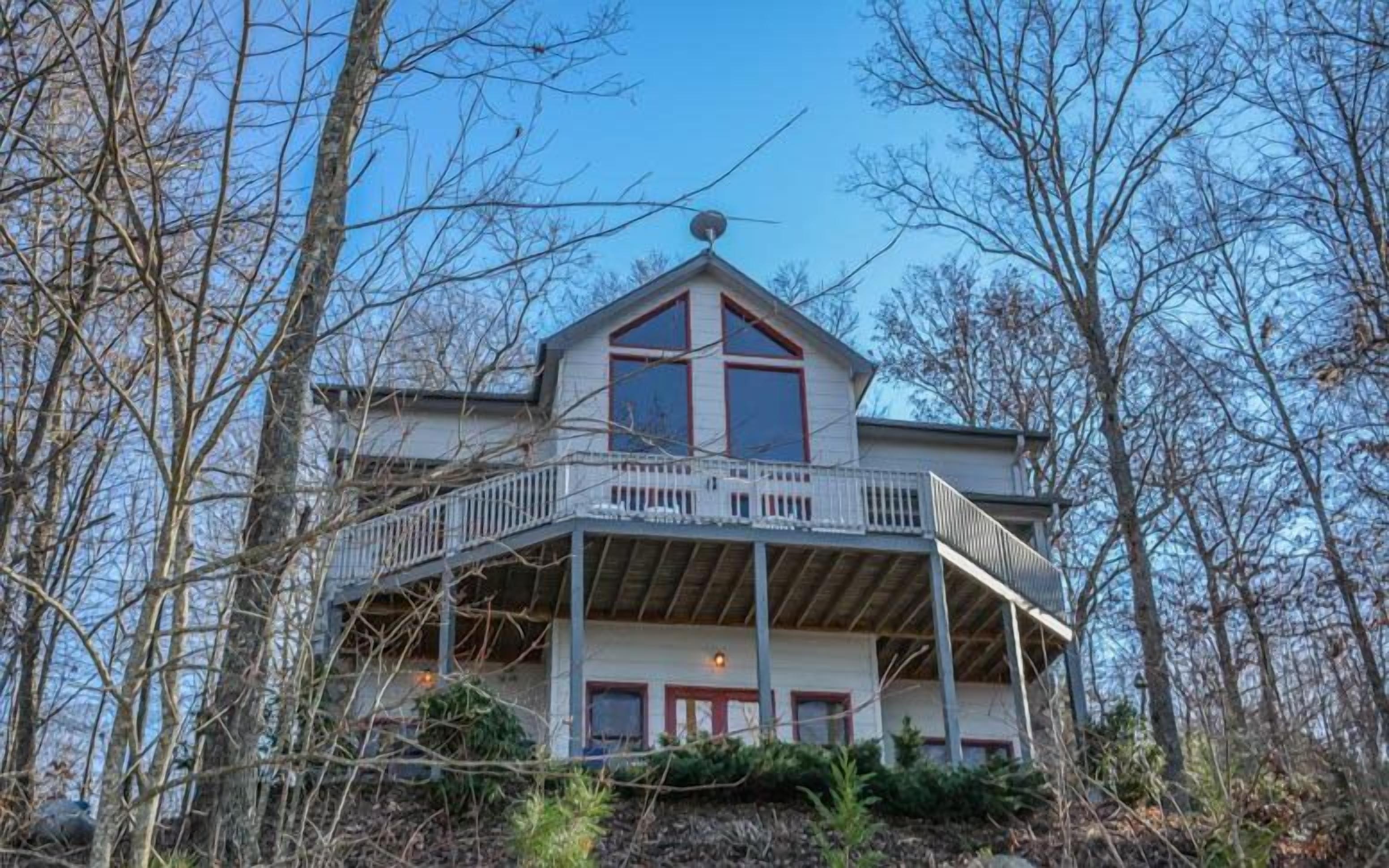 A two-story house with a balcony, surrounded by trees.