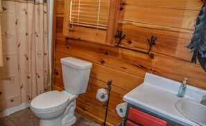 A wooden cabin bathroom with a toilet, a sink, and a shower curtain. - Captain Morley`s Mountain Inn (Morganton)