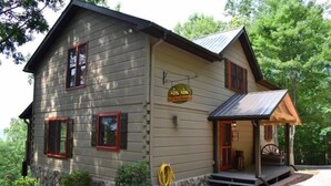 A two-story log cabin with a porch, a sign indicating it is a restaurant, and a small outdoor seating area. - Captain Morley`s Mountain Inn (Morganton)