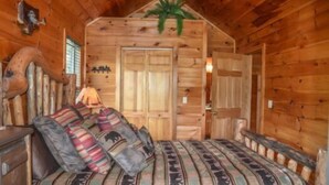 A log cabin room with a bed, a lamp, and a door.