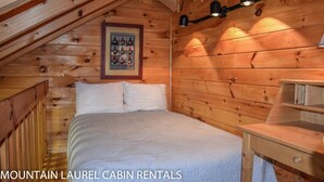 Uma cabana de madeira com uma cama, um criado-mudo e luminárias fixadas na parede.