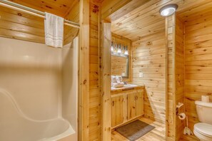 A wooden cabin bathroom with a bathtub, a sink, and a toilet. - Paradise Lodge (Blue Ridge)