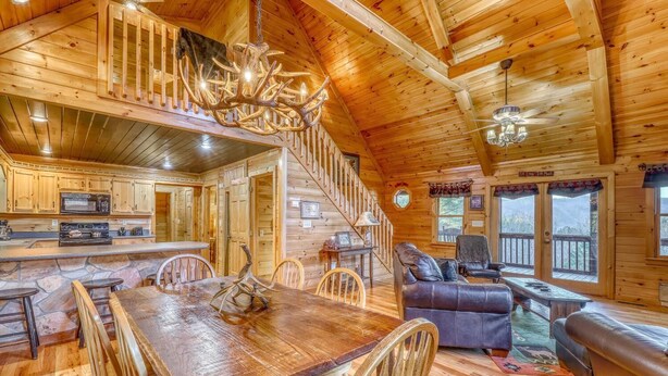 A wooden cabin interior with a dining area, kitchen, and living room. - Paradise Lodge (Blue Ridge)