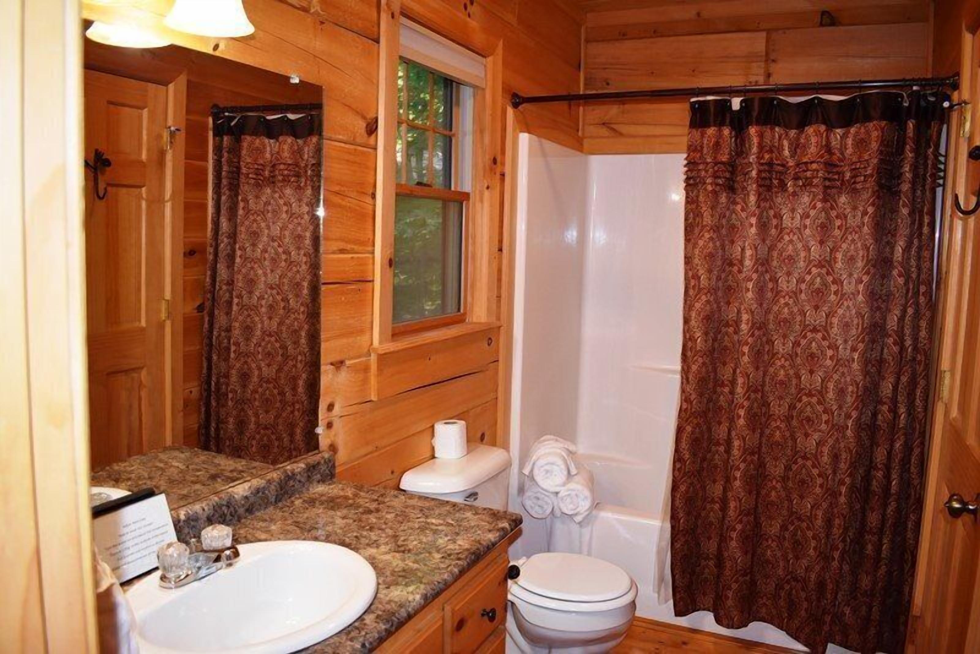 A wooden cabin bathroom with a sink, toilet, and shower.
