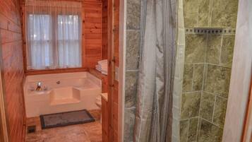 A wooden cabin bathroom with a bathtub, a shower area with tiled walls, and a window with sheer curtains.