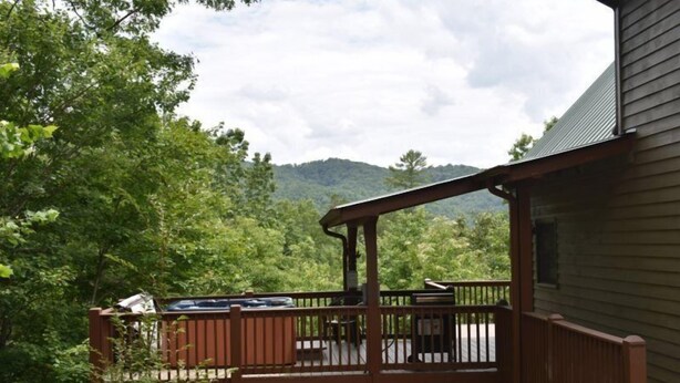 A wooden deck with outdoor seating, surrounded by lush greenery and a mountain backdrop. - Tranquility (Blue Ridge)