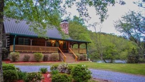 A log cabin with a porch, steps, and a chimney.