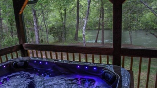 A hot tub with a view of a forest and a river.