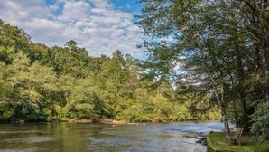 Un río que atraviesa un área boscosa, con un banco a la orilla.