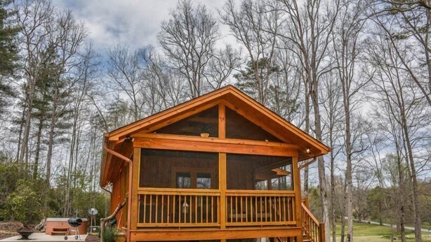 Une cabane en bois dotée d’un balcon, entourée d’arbres.